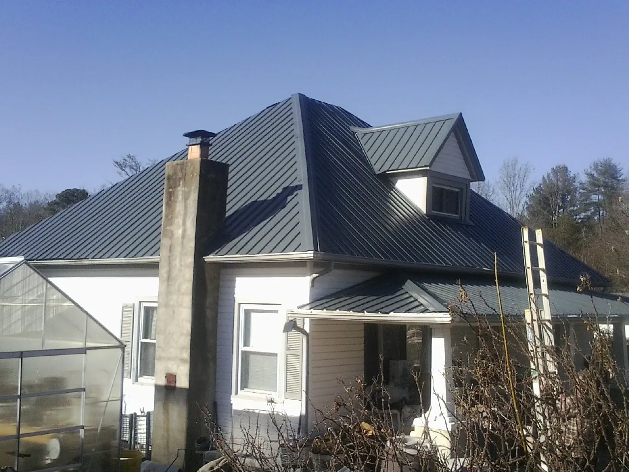 Dark blue standing seam metal roof on a white farmhouse with dormer — Slate & Tile Roof Repair by Roofing Brothers in York Springs