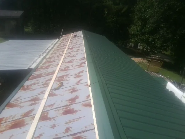 Old rusted panels beside newly installed green metal roofing — Wind Damage Roof Repair by Roofing Brothers in York Springs