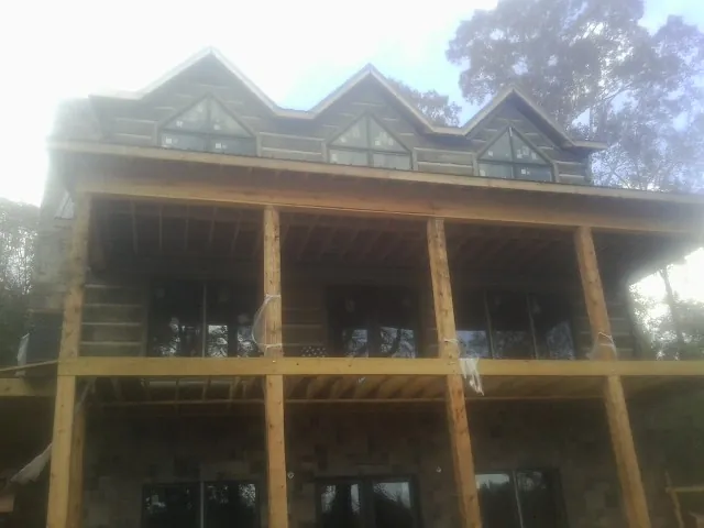 Dormers and porch framing on a large log home under construction — Roof Coating work by our crew in York Springs