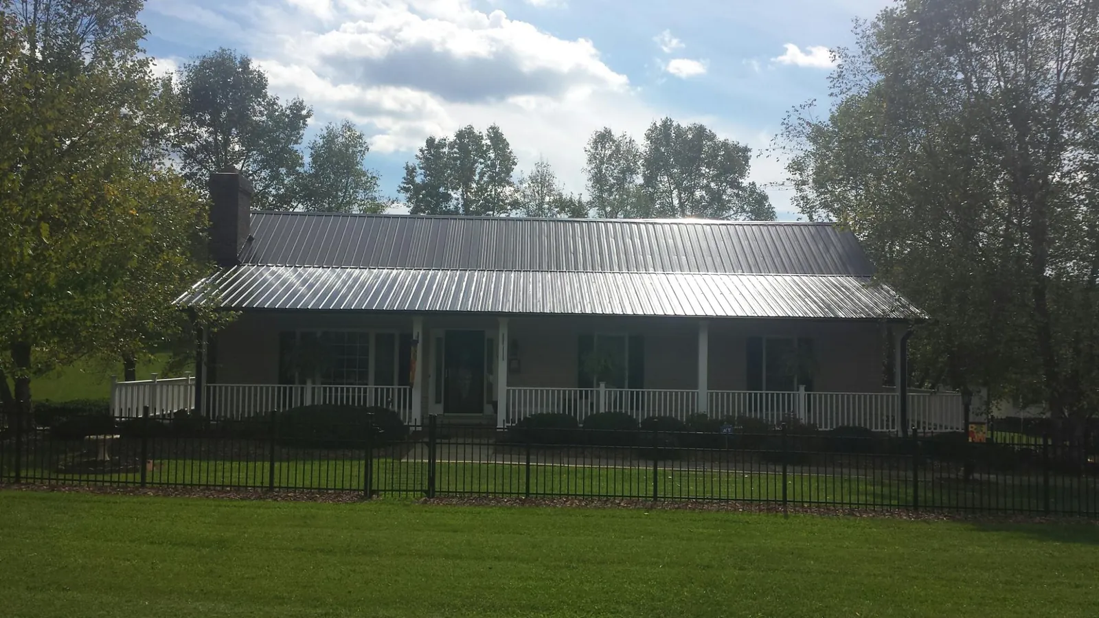 Gray metal roof on a brick ranch with a full width front porch — Gutter Guard Installation work by our crew in York Springs