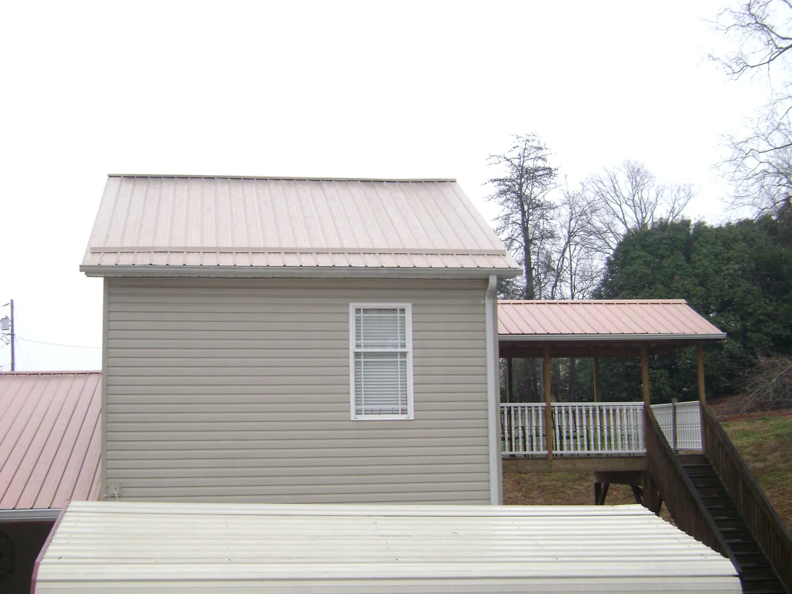 Tan metal roofs on a two story addition and attached porch, from a Roof Replacement job in York Springs